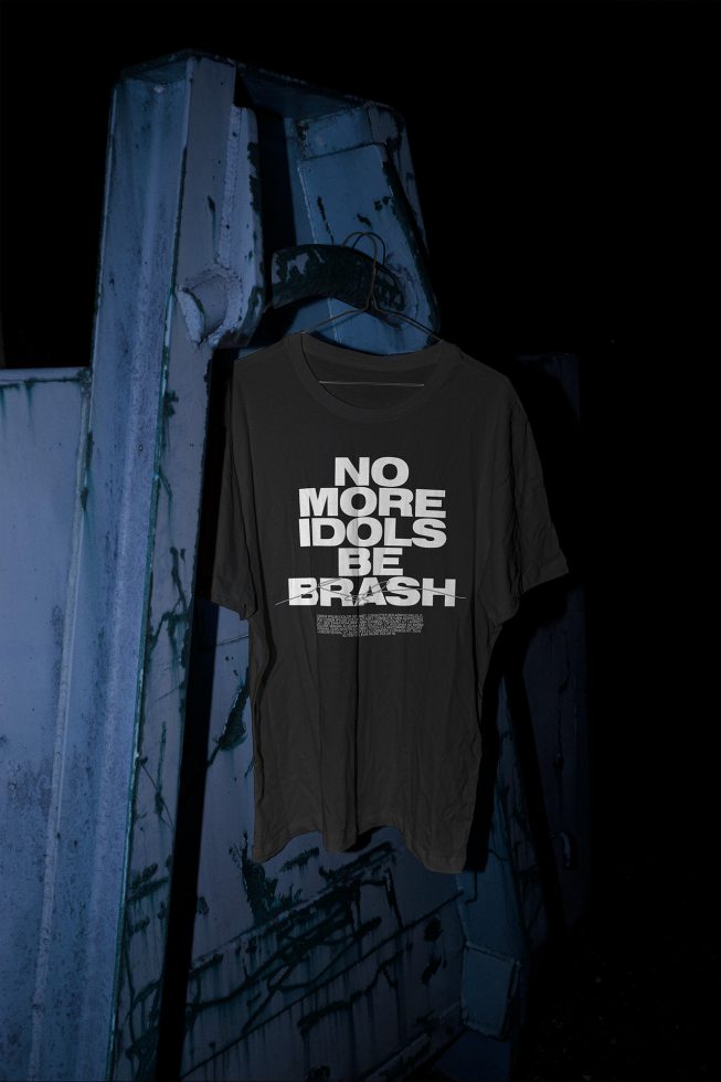 T-shirt mockup hanging on industrial metal door, edgy street style, graphic font design display, night setting, urban fashion presentation.